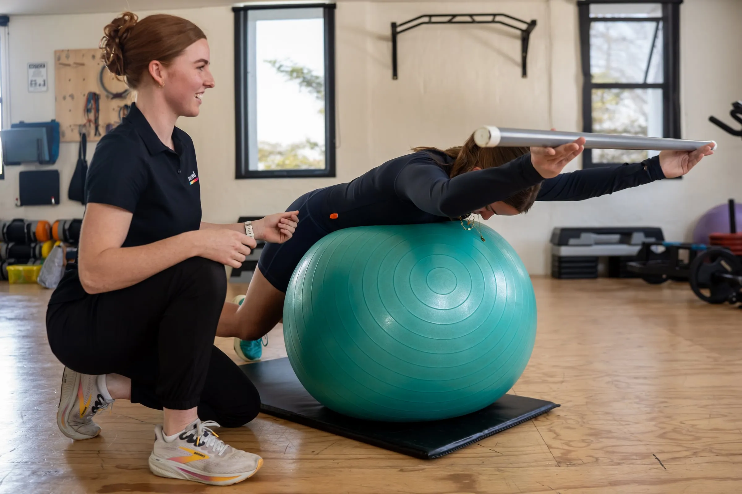 A Movewell biokineticist guiding a client through a supervised exercise on a stability ball
